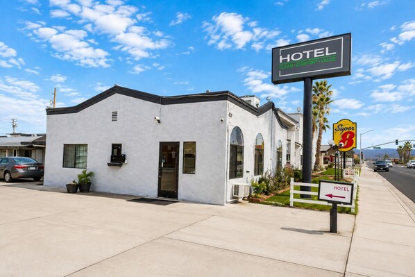 A single-story hotel with a white facade, a black door, and a small porch area.