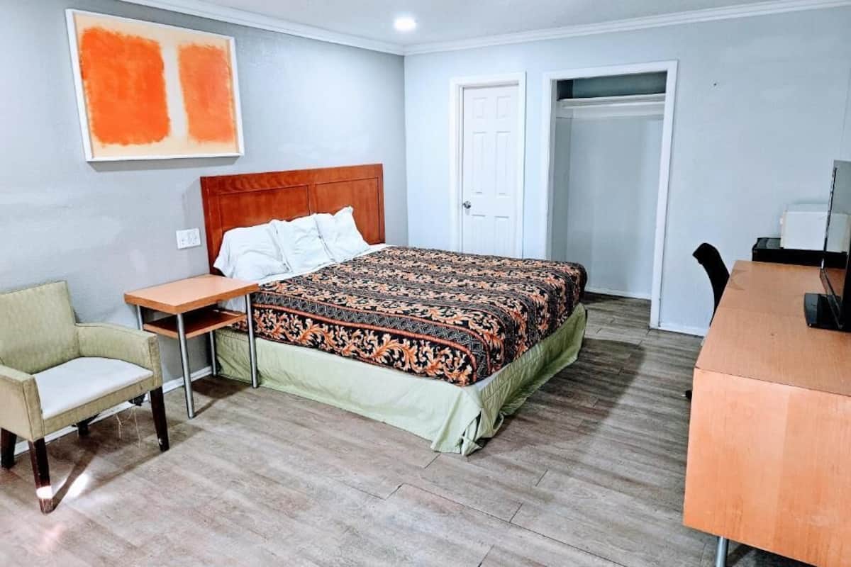 A hotel room with a bed, a desk, a chair, and a door.