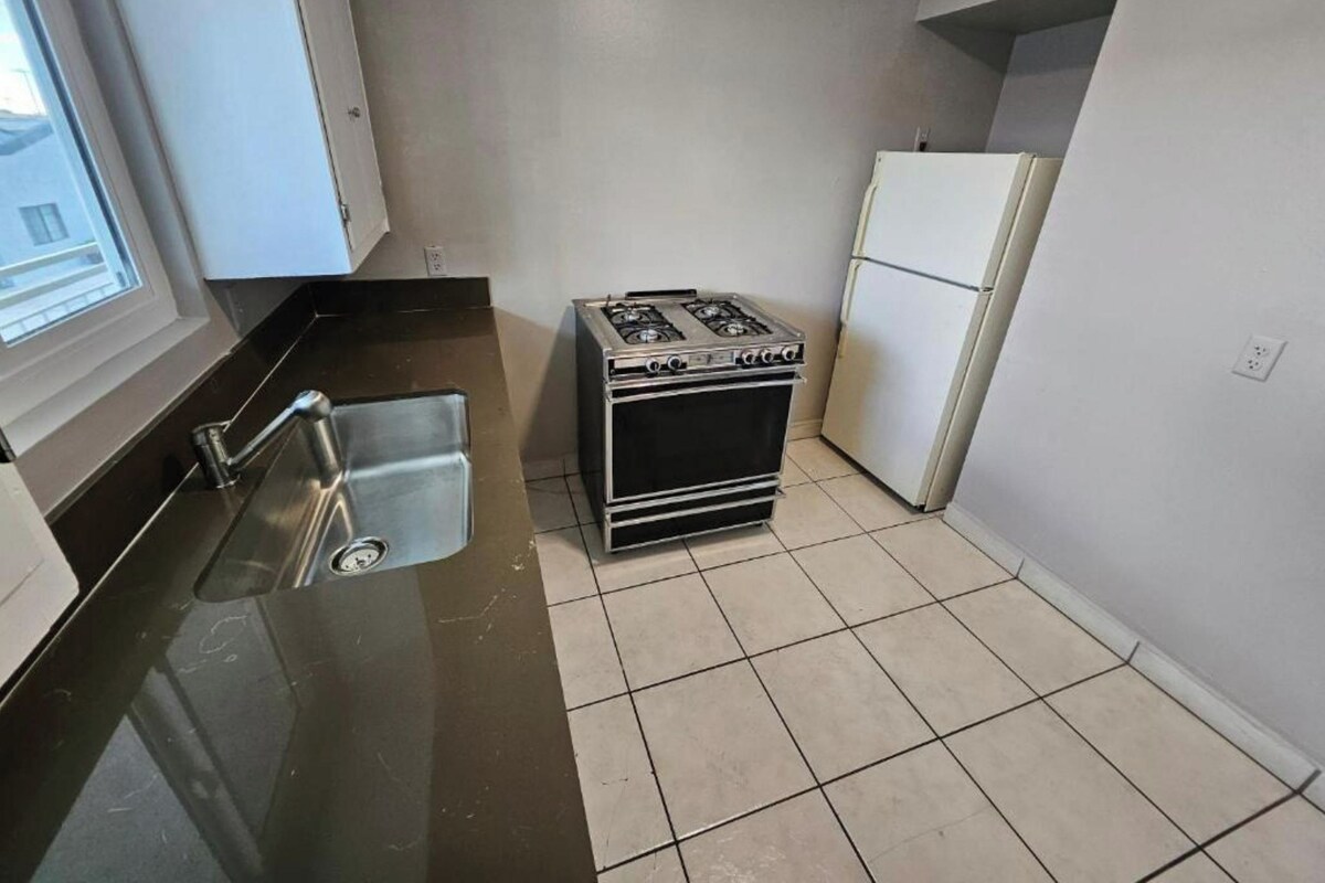 A small kitchen with a sink, stove, and refrigerator.