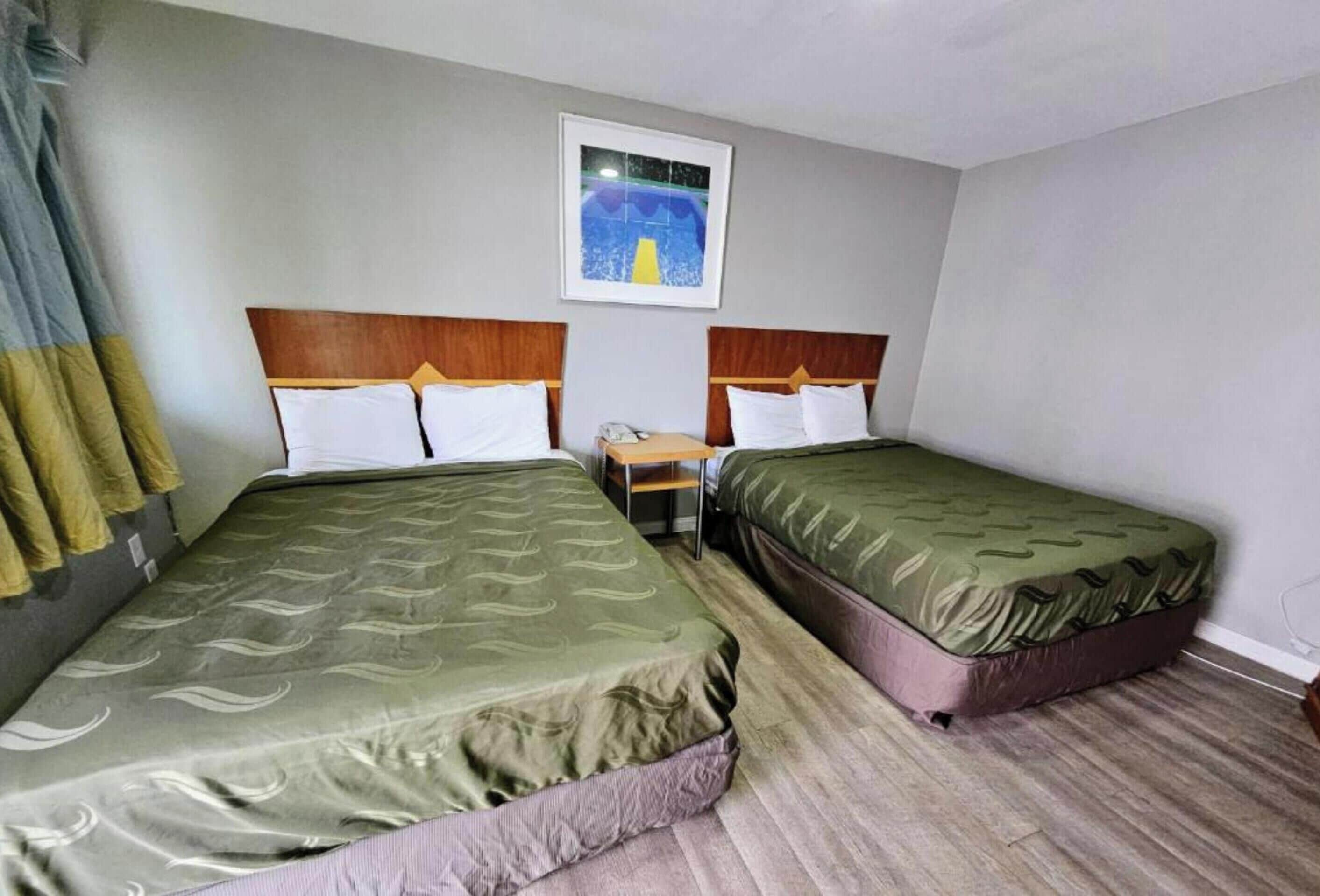 Une chambre d’hôtel avec deux lits, une petite table et un tableau au mur.
