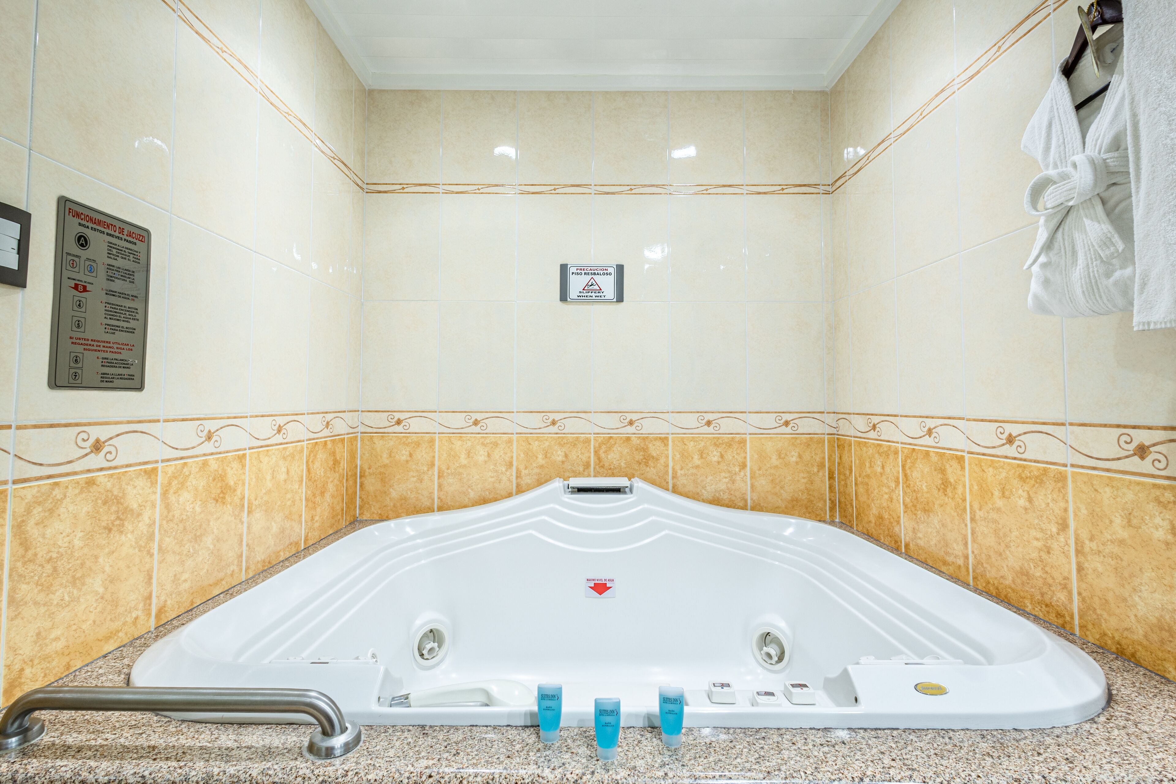 Een spa-ruimte met een groot, wit bad, een handdoekhouder en een bord met veiligheidsinstructies.