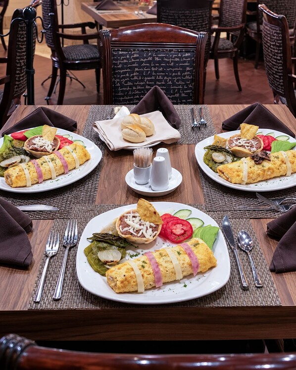 A dining table set with plates of food, including tacos and omelets, in a restaurant setting. - Suites Inn La Muralla Metepec (Toluca)