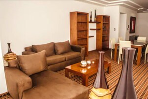 A living room with a brown sofa, a coffee table, two vases, and a bookshelf.