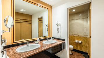 Un baño con dos lavamanos, un espejo grande, un secador de pelo y un inodoro.