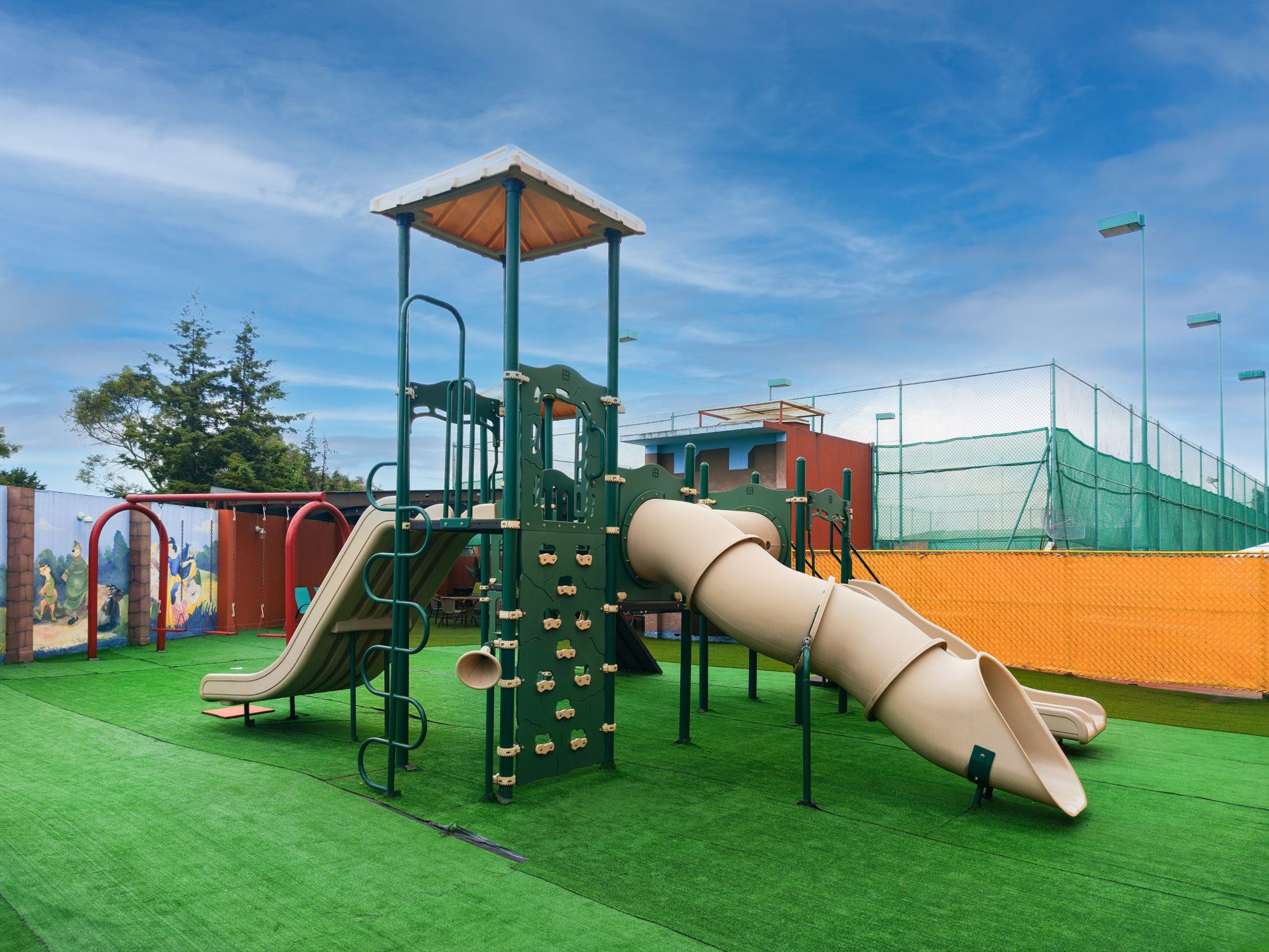 Un parque infantil con tobogán, estructuras para escalar y un área cercada.