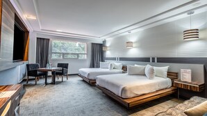 A modern hotel room with two beds, a dining table, and a TV. - Suites Inn La Muralla Metepec (Toluca)