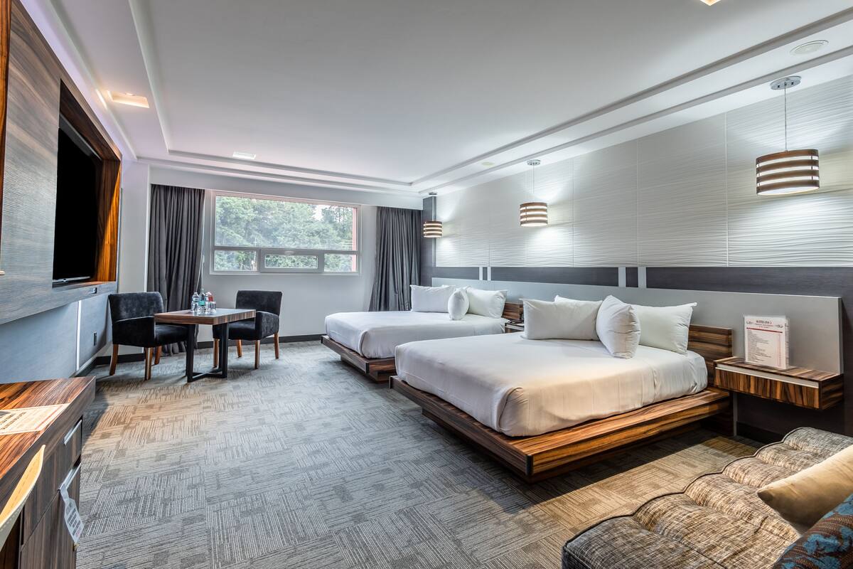 Ett modernt hotellrum med två sängar, ett matbord och en TV.