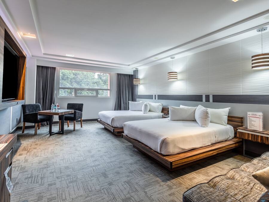 Una habitación de hotel moderna con dos camas, una mesa de comedor y un televisor.