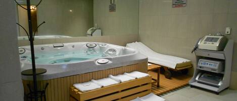 A spa room with a hot tub, a massage table, and a sauna.