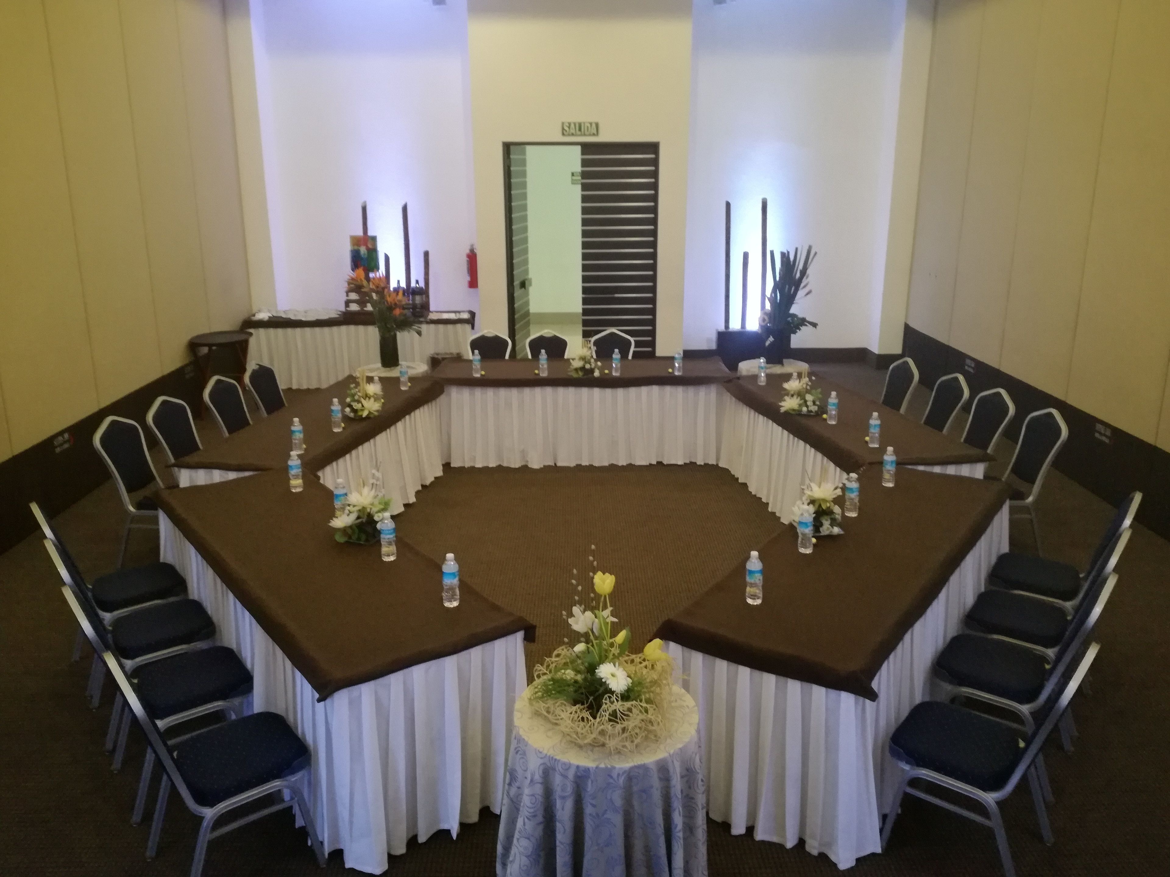 A conference room with a large oval table, white drapes, and black chairs.