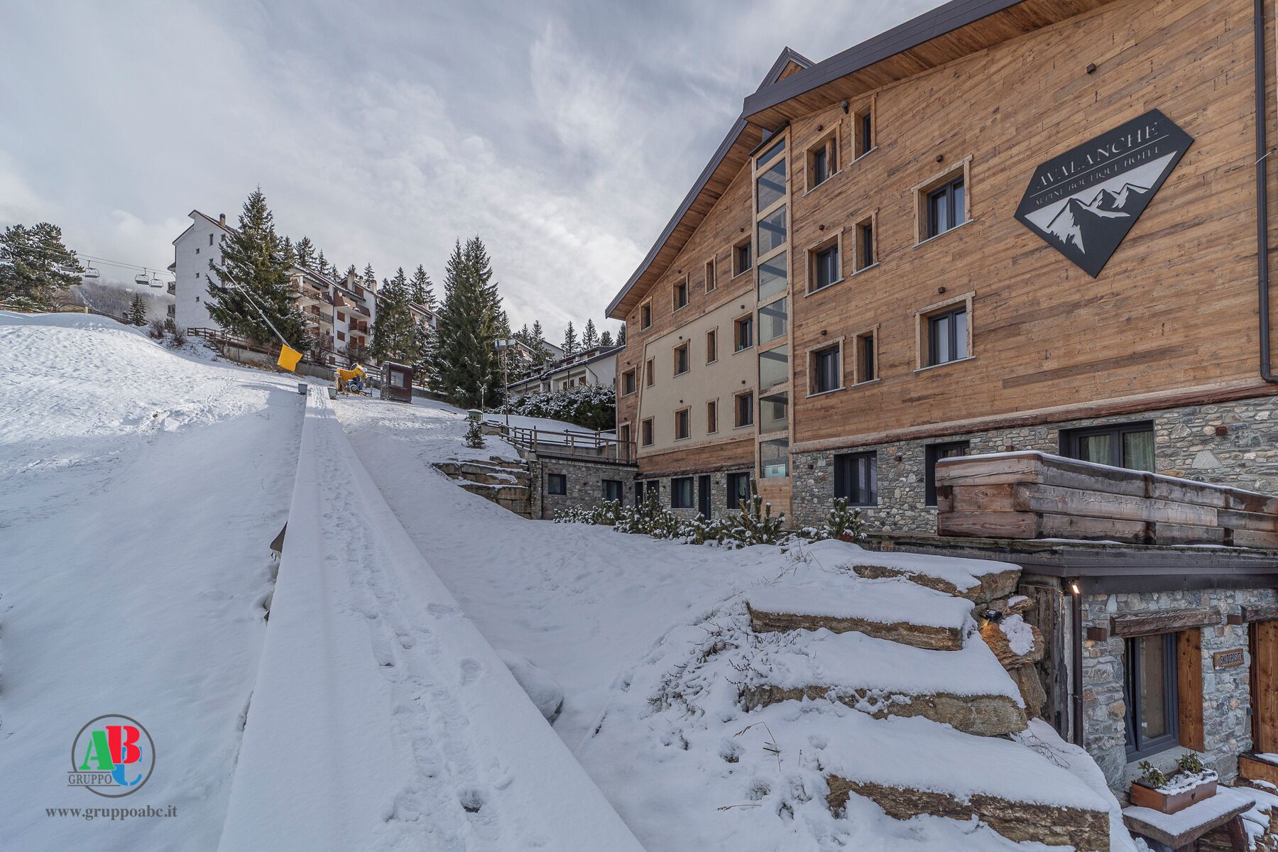 Un centro de esquí cubierto de nieve con un edificio de madera que dice 'BALANCE' y un telesilla al fondo.