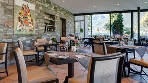 Un restaurante con paredes de piedra, ventanas amplias y mesas dispuestas para comer.