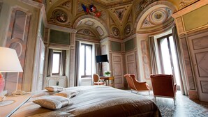 Habitación de hotel con una cama grande, un escritorio, dos sillas y un televisor.