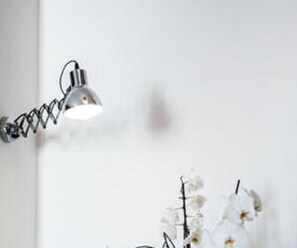 A wall-mounted lamp and a vase with white flowers. - Belmonte Hotel (Favara)