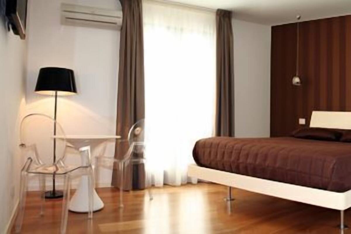 A modern bedroom with a bed, bedside tables, a desk, and a chair.