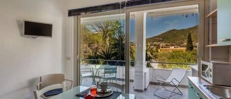 A modern apartment with a balcony, a dining area with a table and chairs, and a kitchen area.