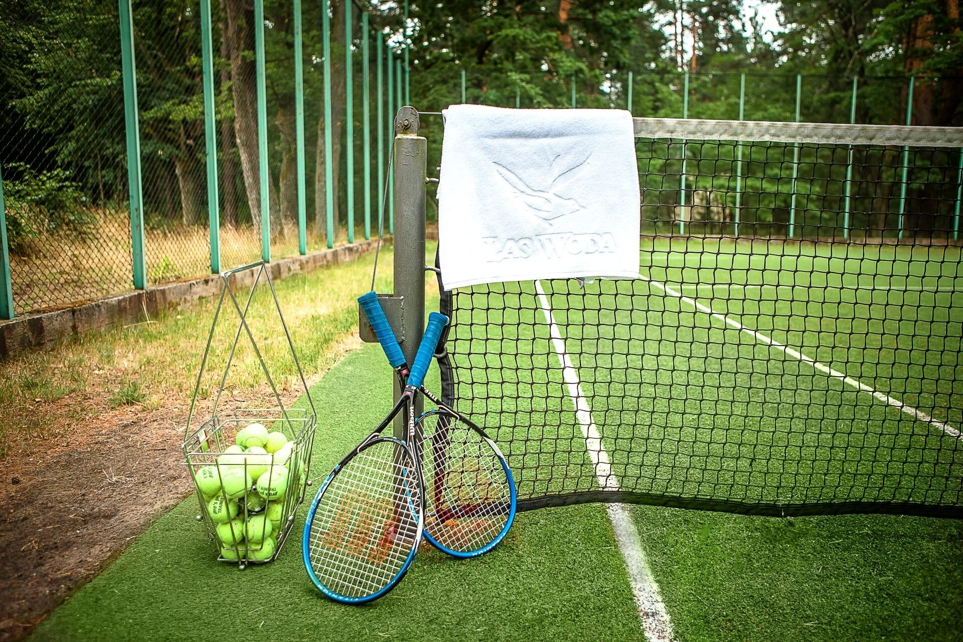 En tennisbane med et net, et håndklæde og tennisraketter.