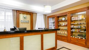 Zona de recepción de hotel con mostrador de madera, un reloj y una exhibición de licores.