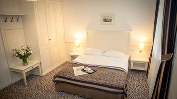 Una habitación de hotel con cama, mesitas de noche, armario y un cuadro en la pared.
