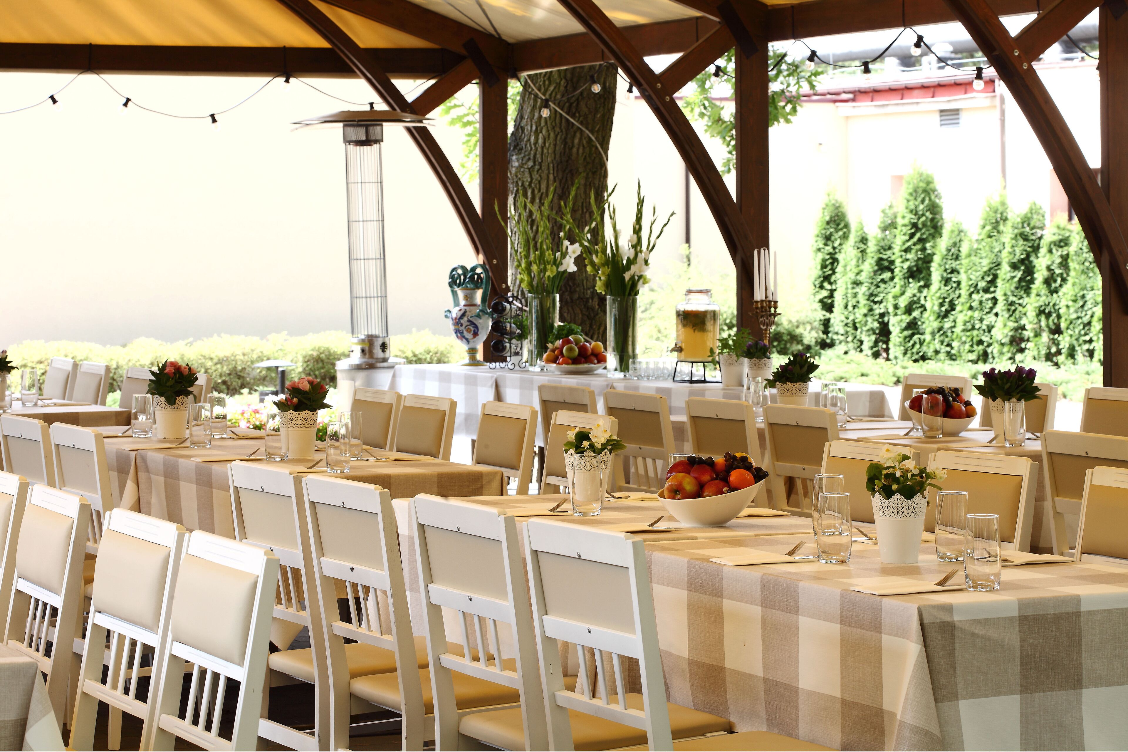 Zona de dinar amb taules preparades per a convidats, amb mantell de taula a quadres, caires blancs i centrals florals.