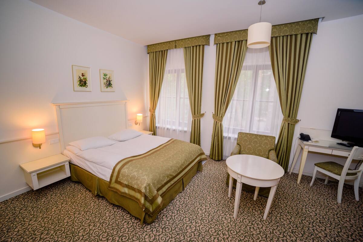 Une chambre d’hôtel comprenant un lit, une table de chevet, une lampe, une chaise, un bureau et un téléviseur.