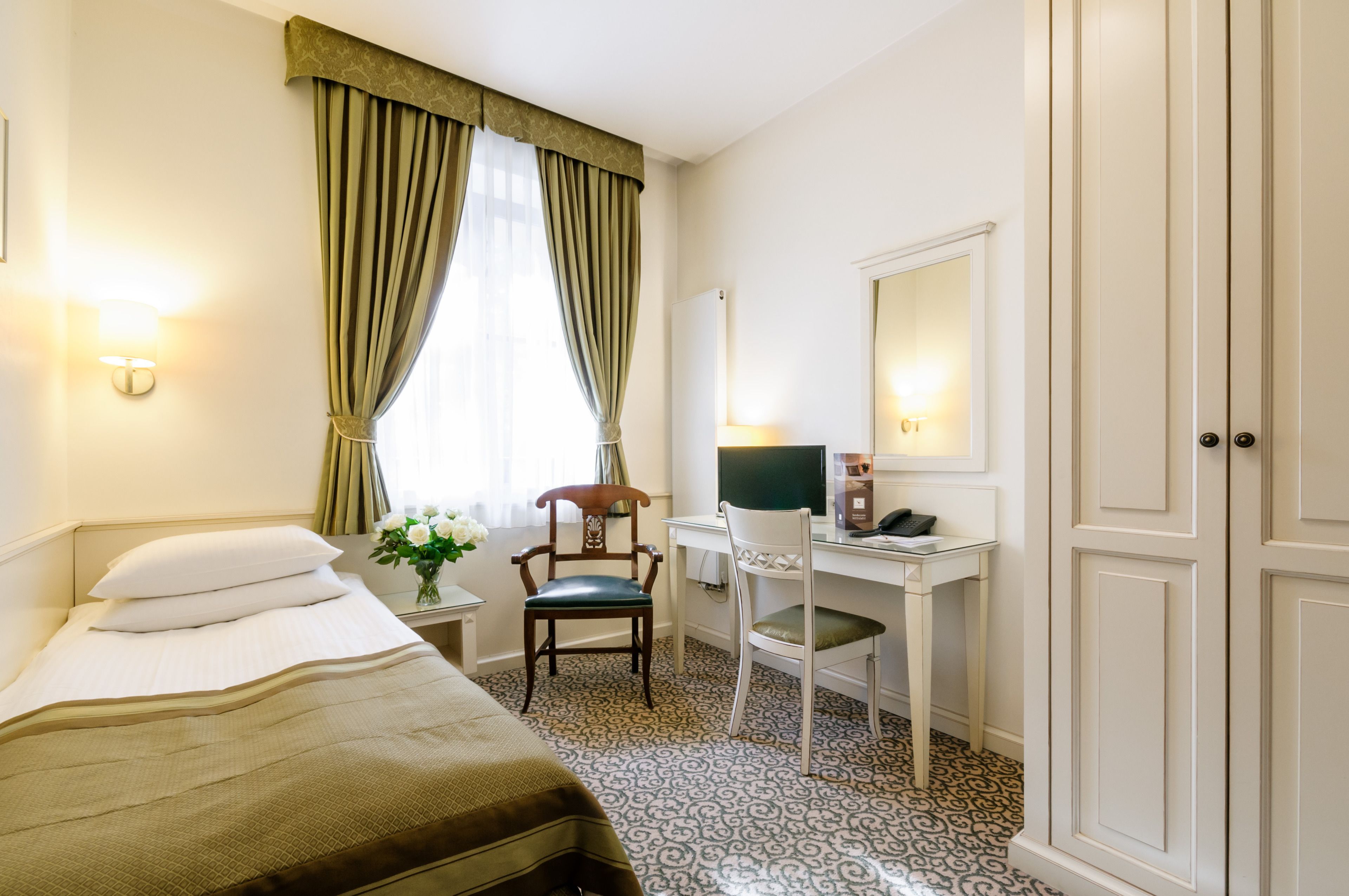 Une chambre d’hôtel comprenant un lit, un bureau, une chaise, un miroir et une armoire.