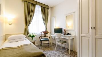 Une chambre d’hôtel comprenant un lit, un bureau, une chaise, un miroir et une armoire.