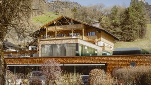 Una cabaña de madera con balcón, ventanas grandes y garaje.