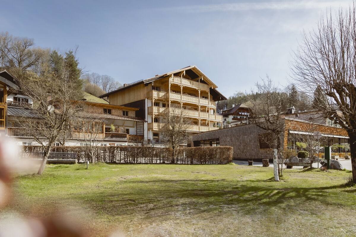 Un immeuble en bois à plusieurs étages, doté de balcons, entouré d’arbres et d’une zone herbeuse.