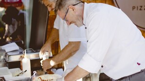 Un cocinero preparando comida en una barra con una pared de madera y un letrero que dice "H PIZZA".