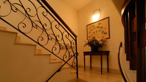 A staircase with ornate black railings, a wall-mounted light fixture, and a framed picture with text and flowers. - Albergo Ristorante Umbria (Città di Castello)