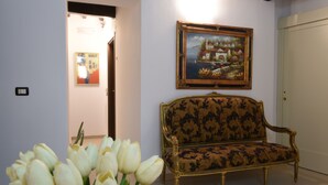 A room with a sofa, a painting on the wall, and a vase of tulips. - Albergo Ristorante Umbria (Città di Castello)