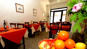 A dining area with tables set for a meal, a fruit bowl on the table, and a window with a view. - Albergo Ristorante Umbria (Città di Castello)