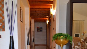 A hallway with a tiled floor, a decorative rug, and a potted plant. - Villa Ottavia (Noto)