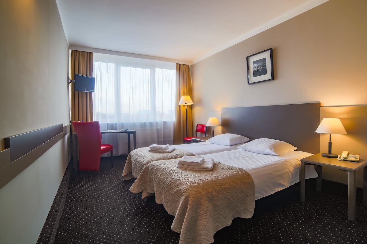 Une chambre d’hôtel avec deux lits, un bureau, une chaise et un téléviseur.