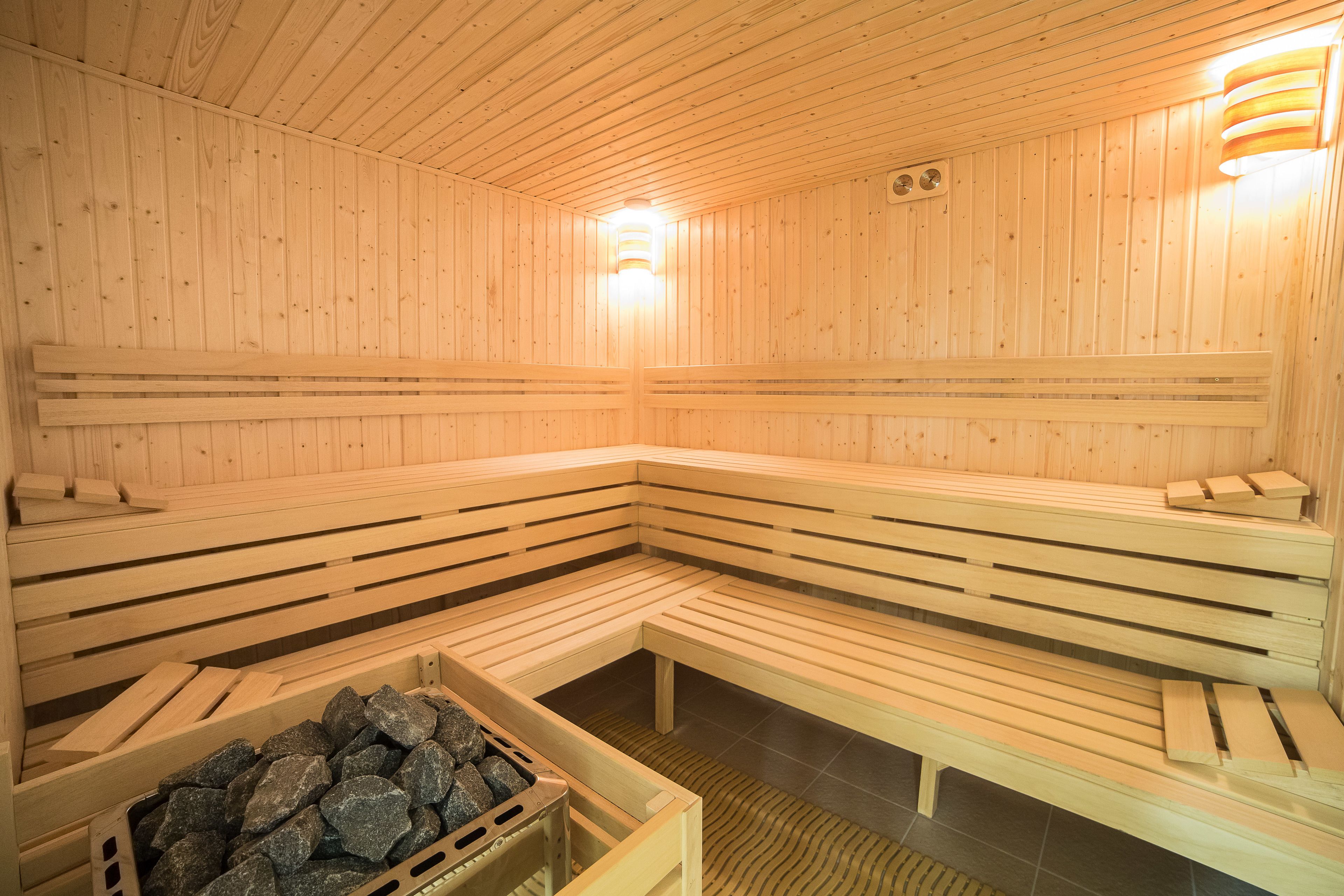 En träbeklädd bastu med bänkar och en behållare fylld med stenar.