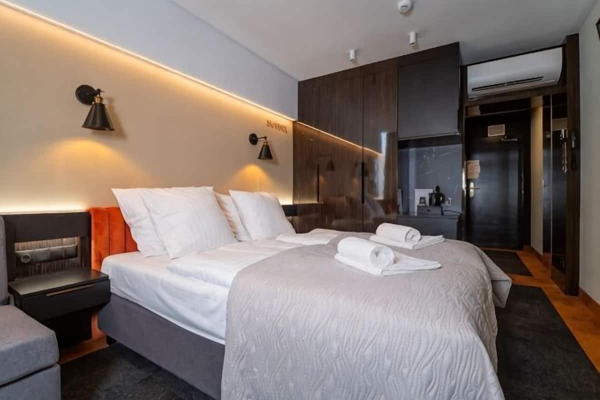 Une chambre d’hôtel moderne, dotée d’un grand lit, de tables de chevet, d’un bureau et d’une armoire.