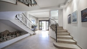 A spacious interior with a curved staircase, a stone pathway, and a view into the adjacent room. - El Coso Hotel (Valencia)