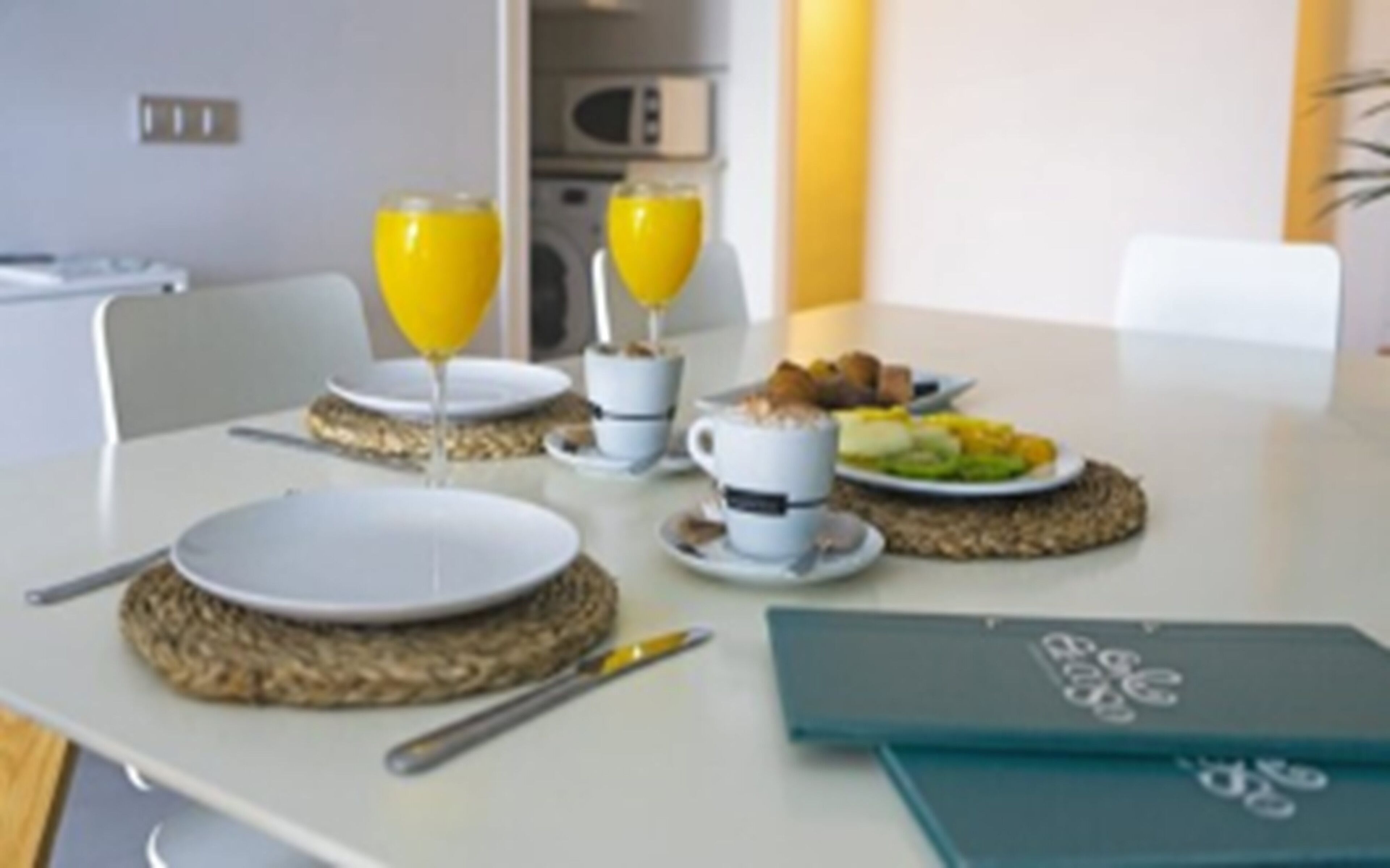 A breakfast setup with plates, cups, and a fruit plate on a table.