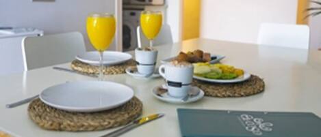 Une table mise pour le petit-déjeuner, avec des assiettes, des tasses et une assiette de fruits.