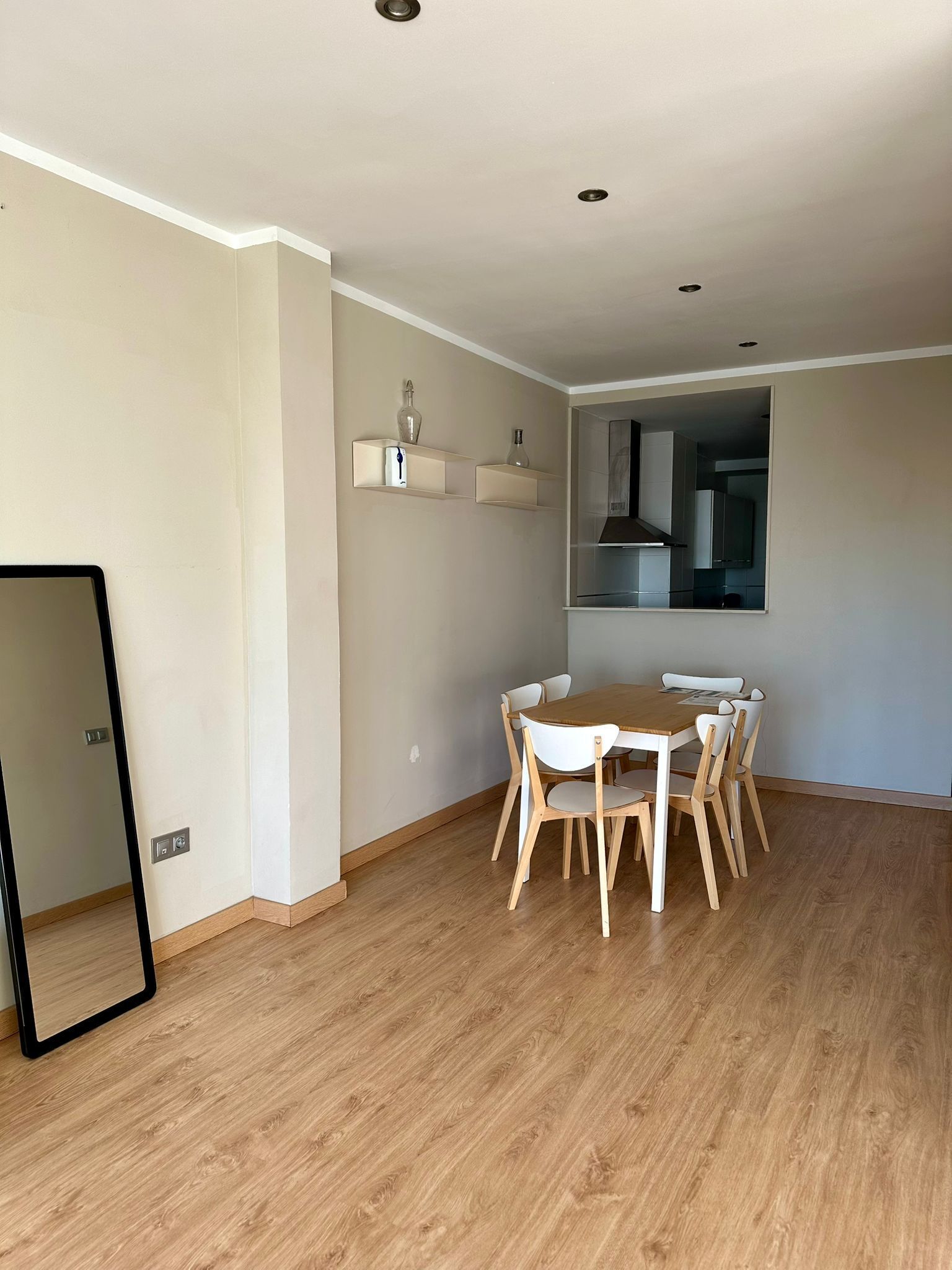 Ein stilvoller Essbereich mit Holztisch und -stühlen, eine durchgehende Tür zur Küche und ein Spiegel an der linken Wand.