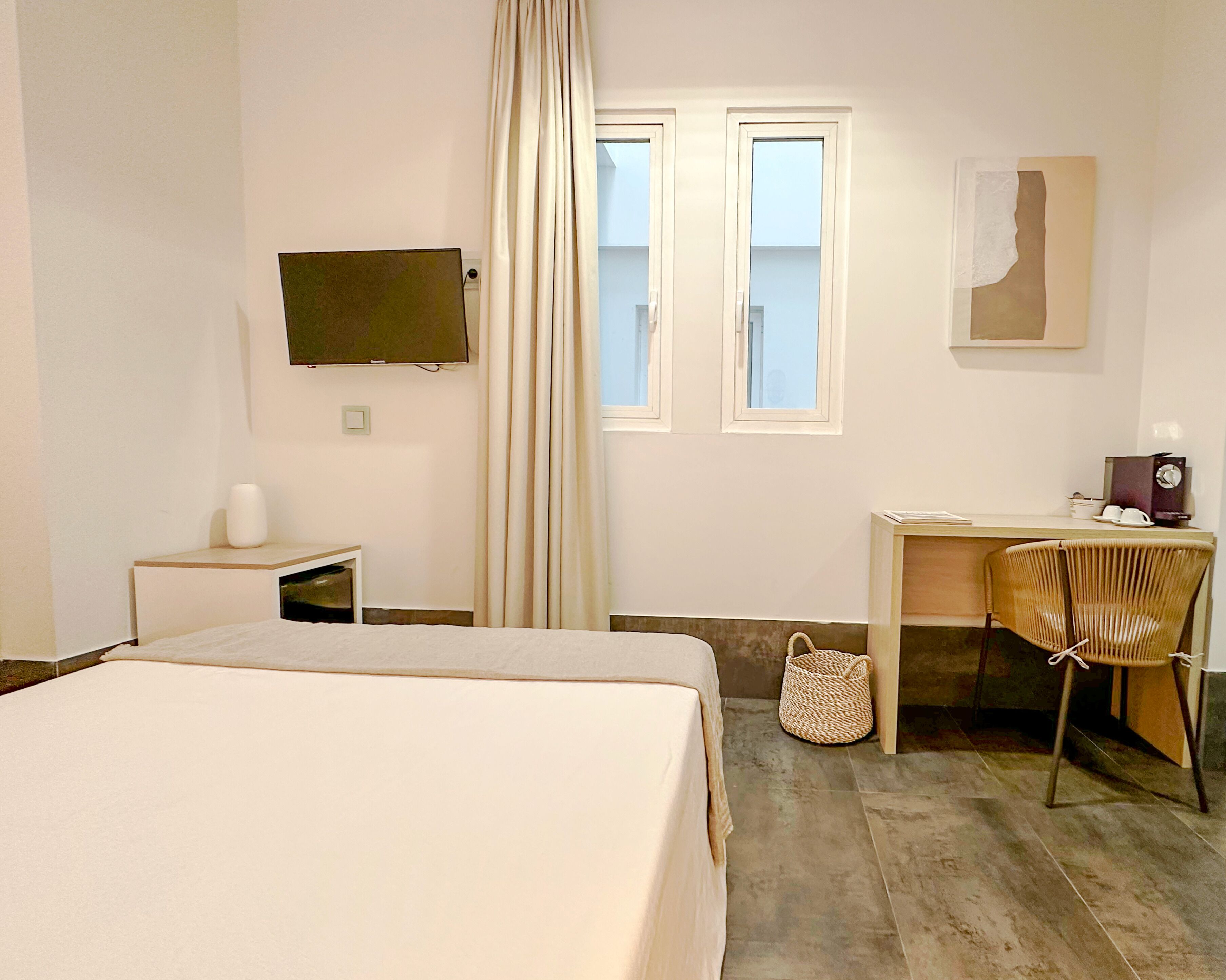 A hotel room with a bed, a desk, a chair, a television, and a window with curtains.