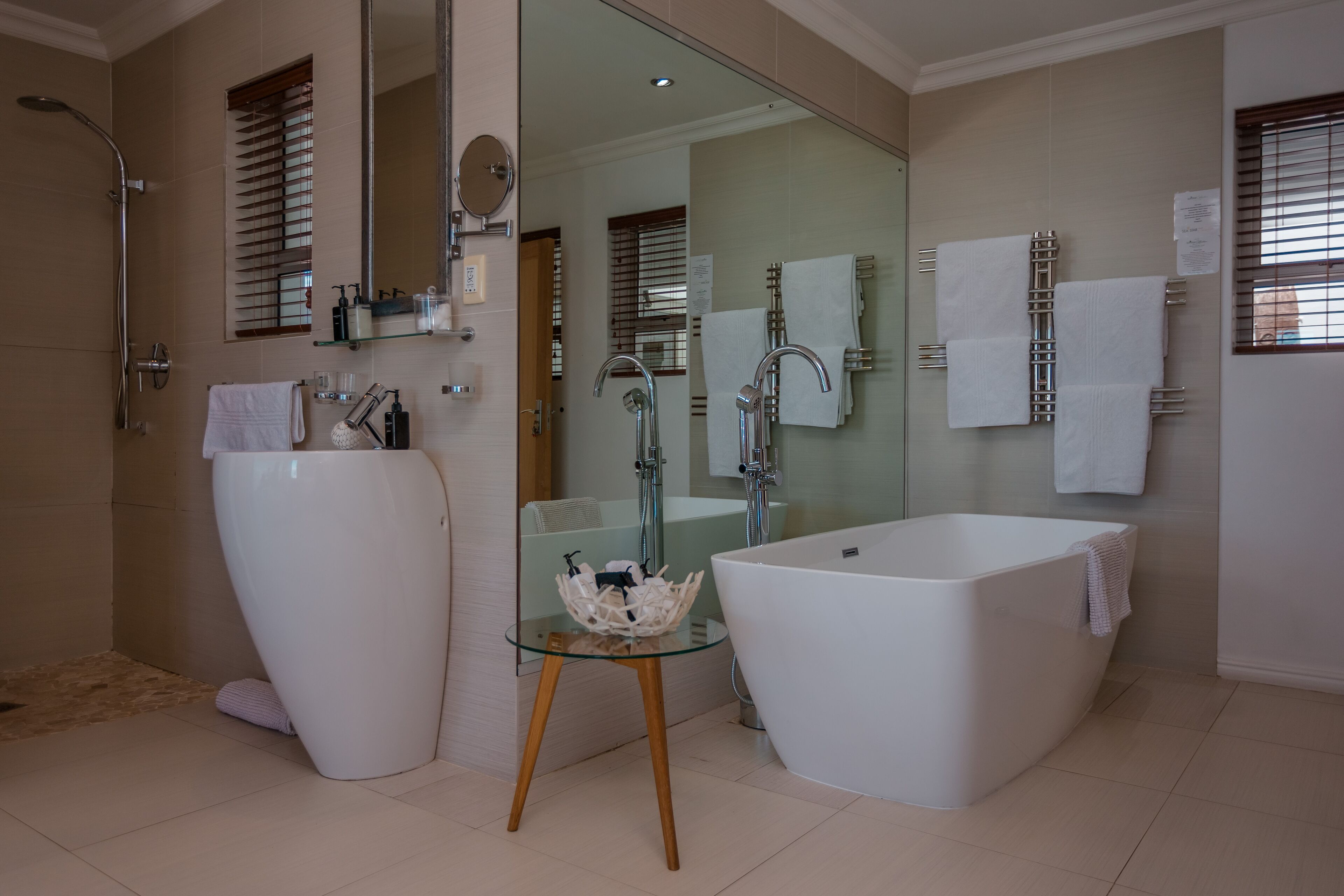 Un baño moderno con una bañera independiente grande, ducha con cerramiento de vidrio y tocador con espejo amplio.