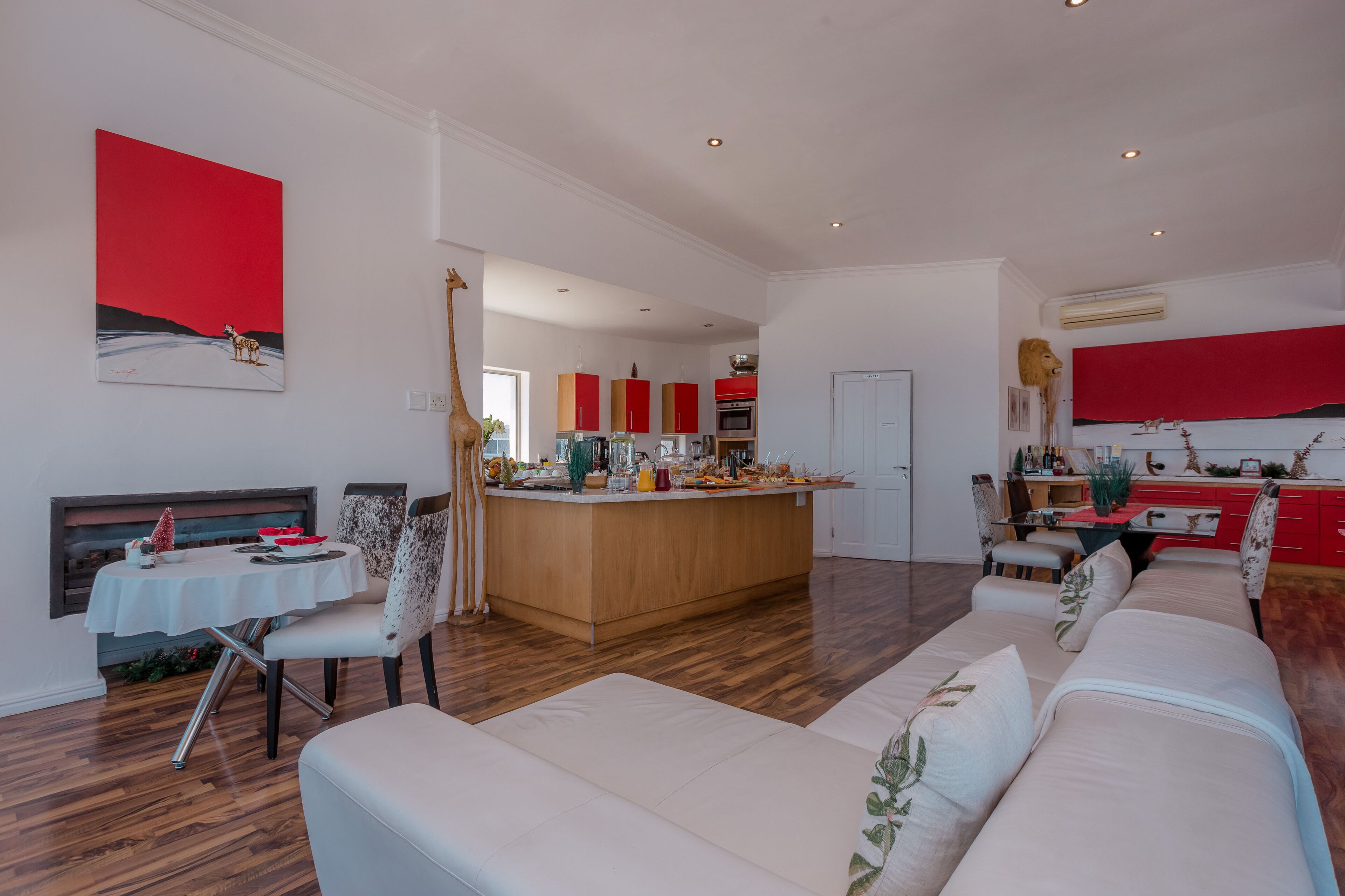 Un salón amplio con un sofá grande, una mesa de comedor y una cocina con armarios rojos y una isla central.