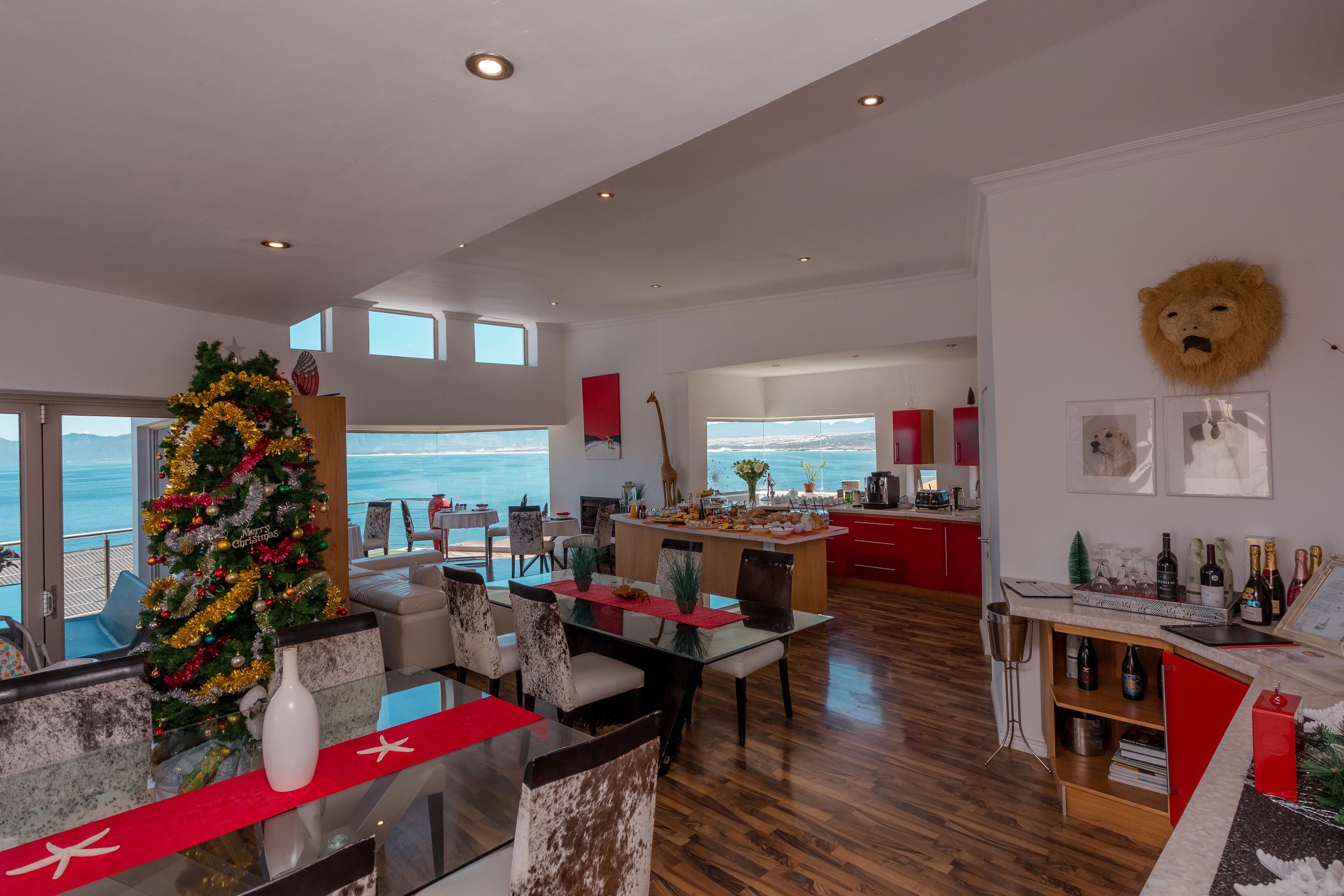 Un amplio salón con piso de madera, un árbol de Navidad y vista al océano.