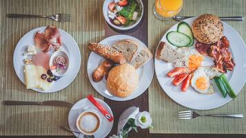A breakfast setting with plates of food, a cup of coffee, and a glass of orange juice.