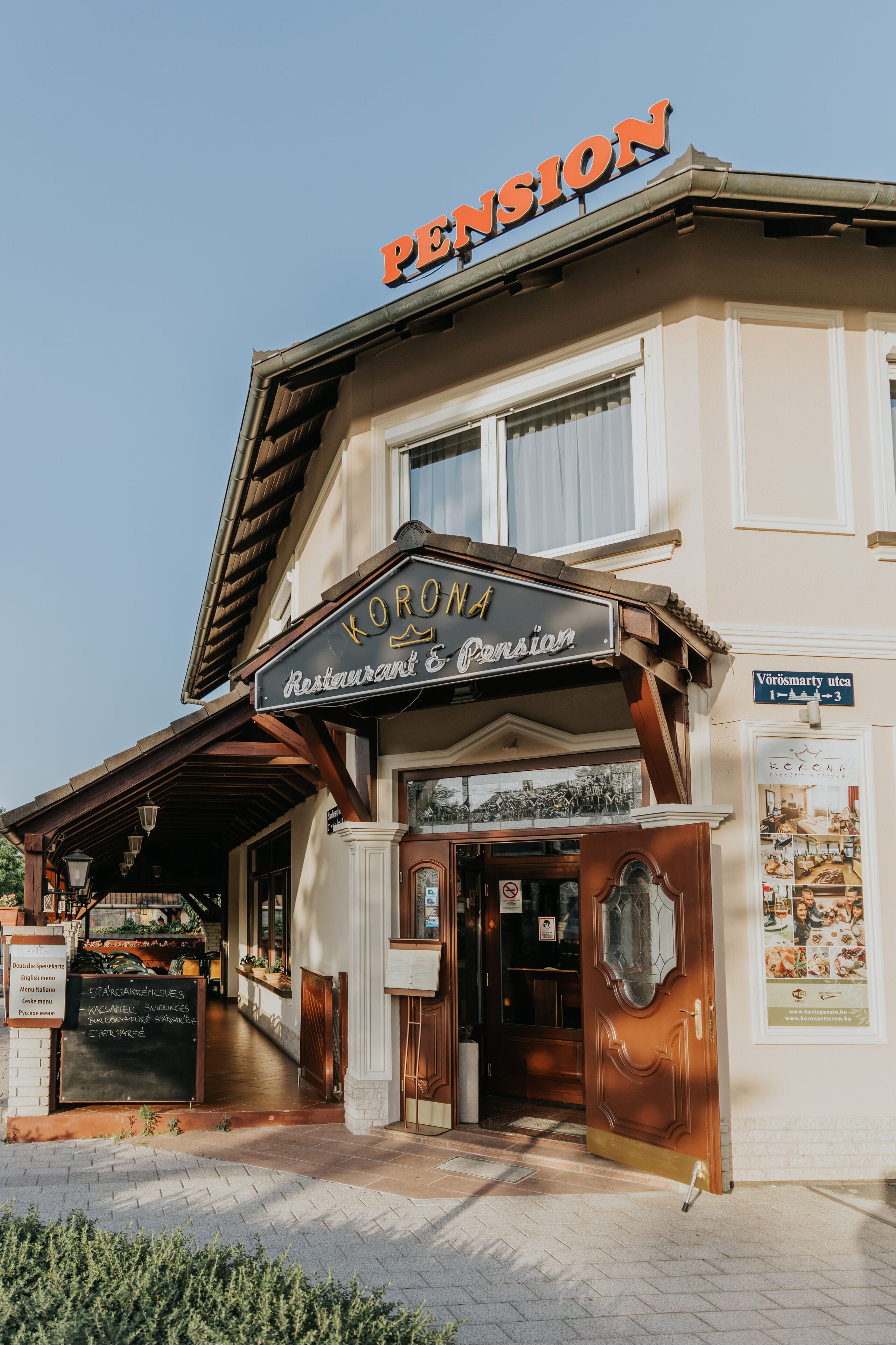 Un bâtiment sur lequel on peut lire les inscriptions « Pension » et « Corona Restaurant & Pension ».