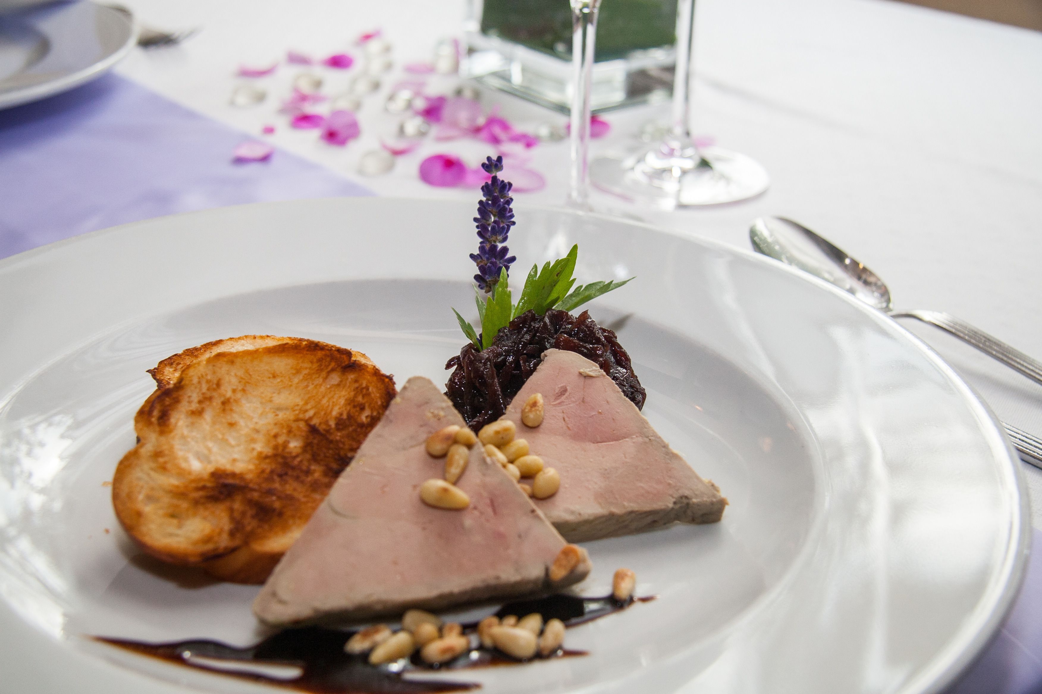 A plate of food with a slice of toast, a piece of meat, and a decorative flower.