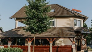 A two-story building with a tiled roof, a sign reading "Pension," and a clock tower. - Korona Pension Restaurant (Hévíz)