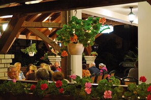 A restaurant with wooden beams, hanging plants, and outdoor seating. - Korona Pension Restaurant (Hévíz)